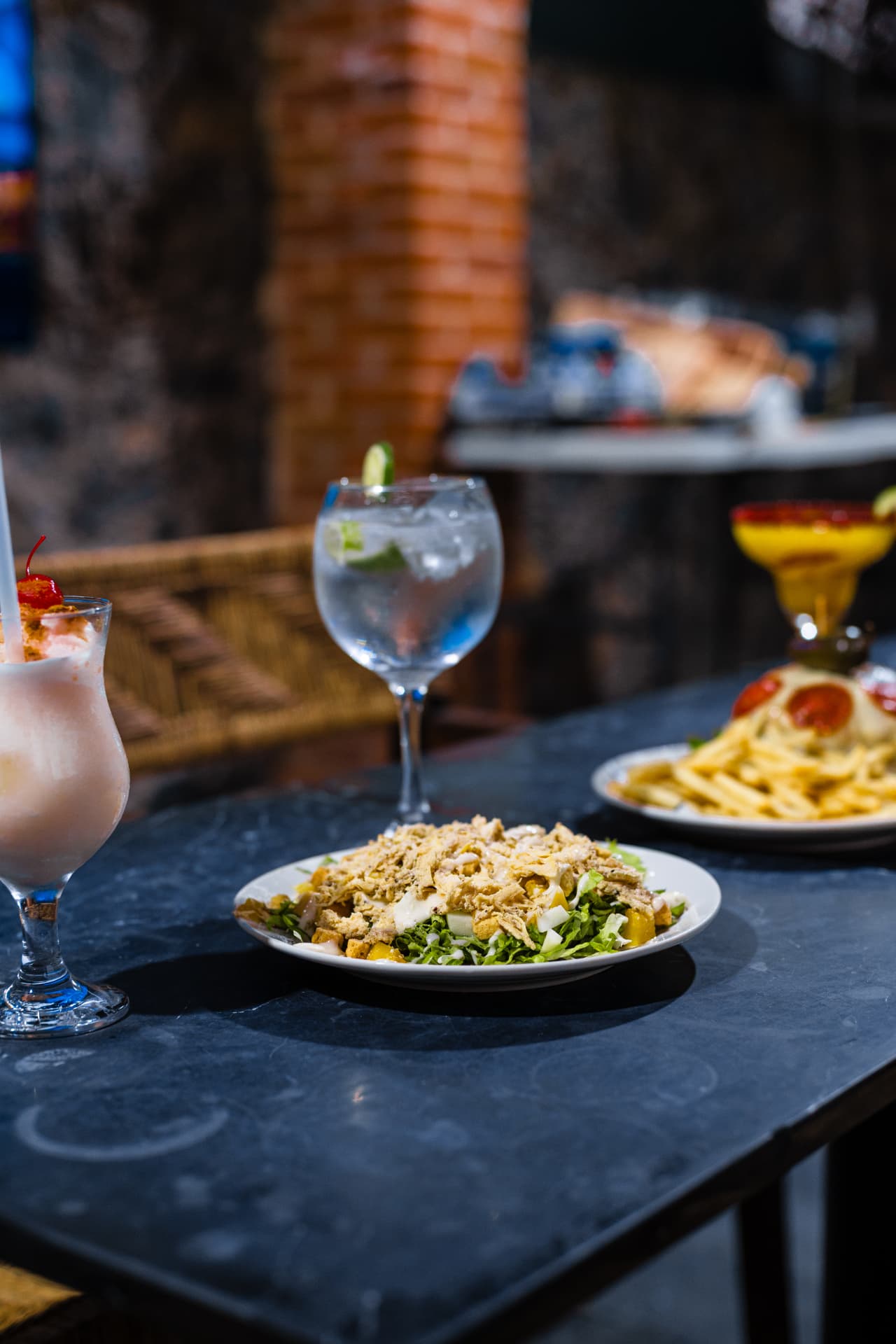Ensalada, pasta y cocteles servidos en una mesa del restaurante de Casa Arcos