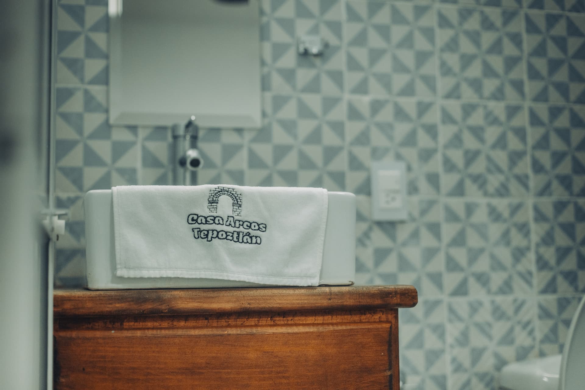Baño con azulejo geométrico y toalla bordada de Casa Arcos Tepoztlán