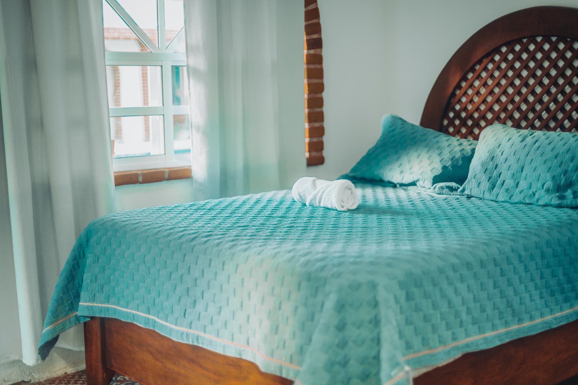 Cama matrimonial de la Doble Deluxe con cabecera de madera y colcha turquesa